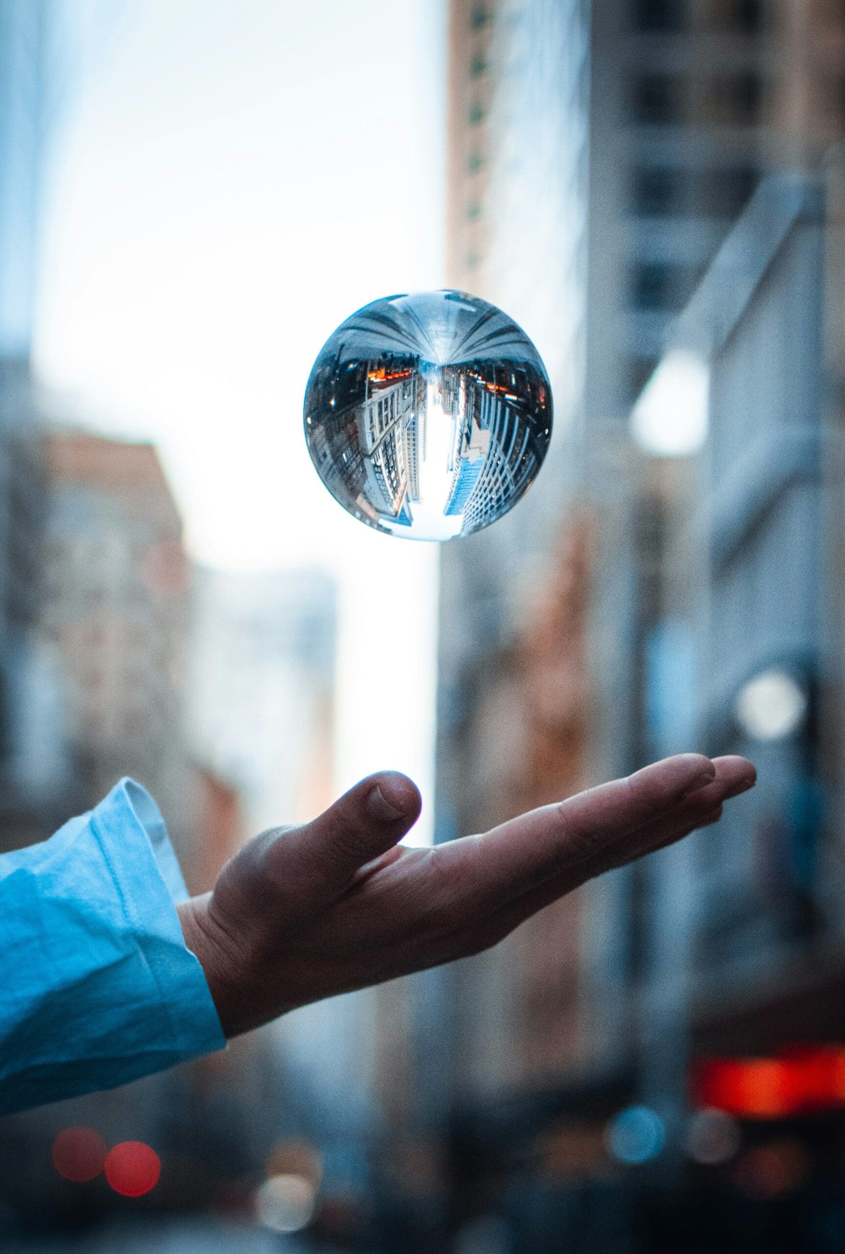 Person’s hand under a levitating glass orb reflecting a city street upside down—symbolizing distorted perspective and the illusion of foresight.