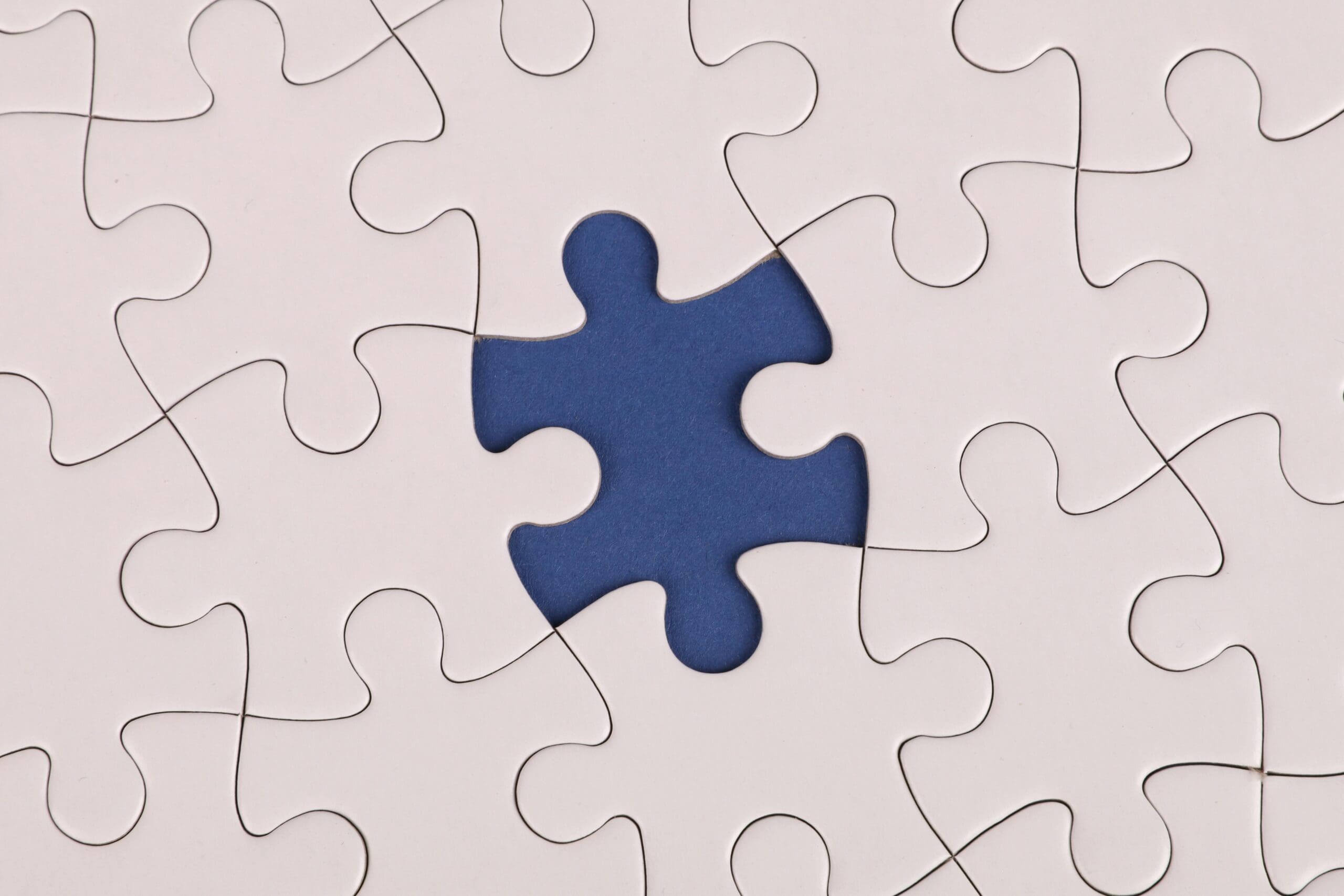 Close-up of a white puzzle with one blue piece missing in the center
