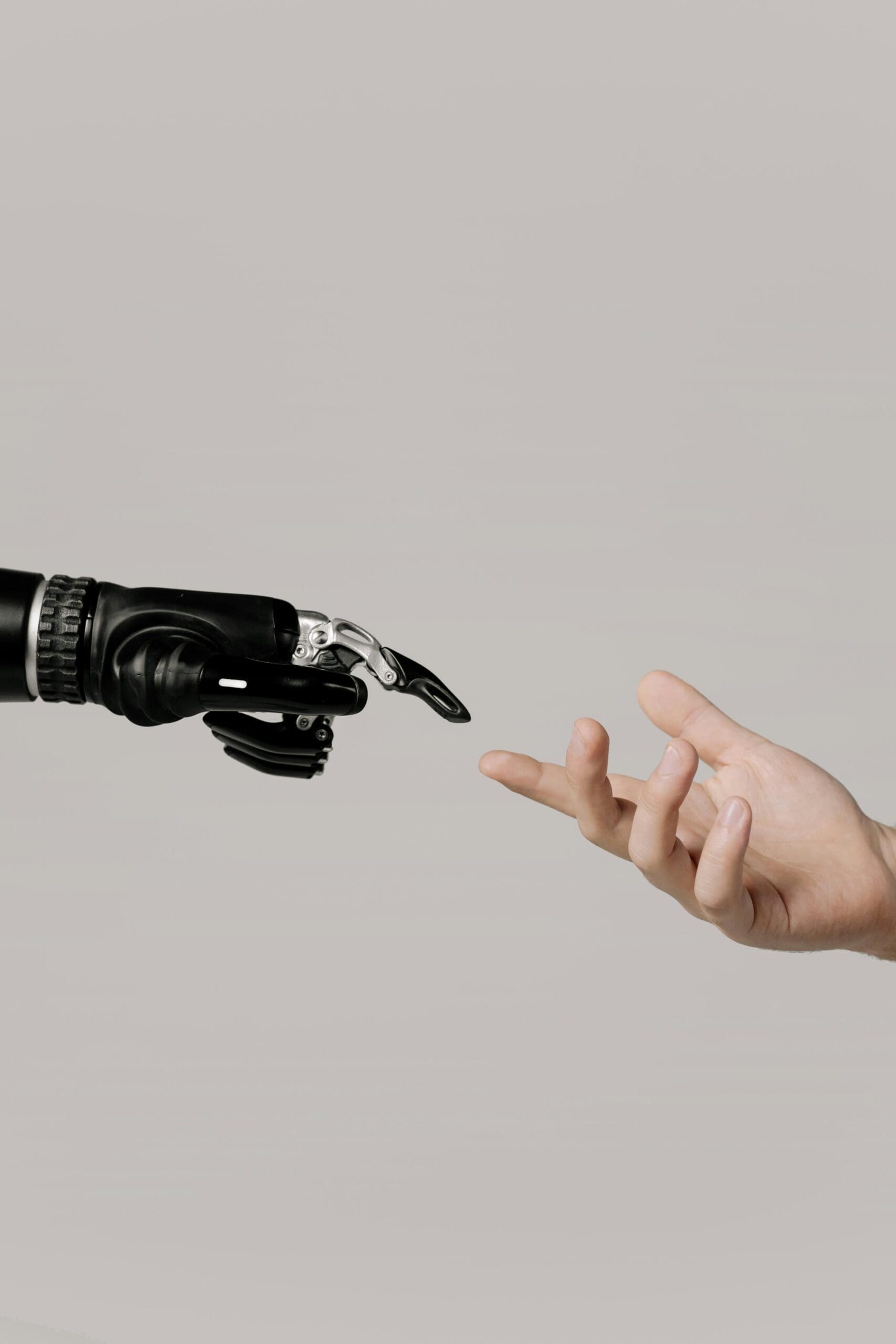 A robotic hand reaching toward a human hand against a neutral background, evoking themes of technology and humanity.