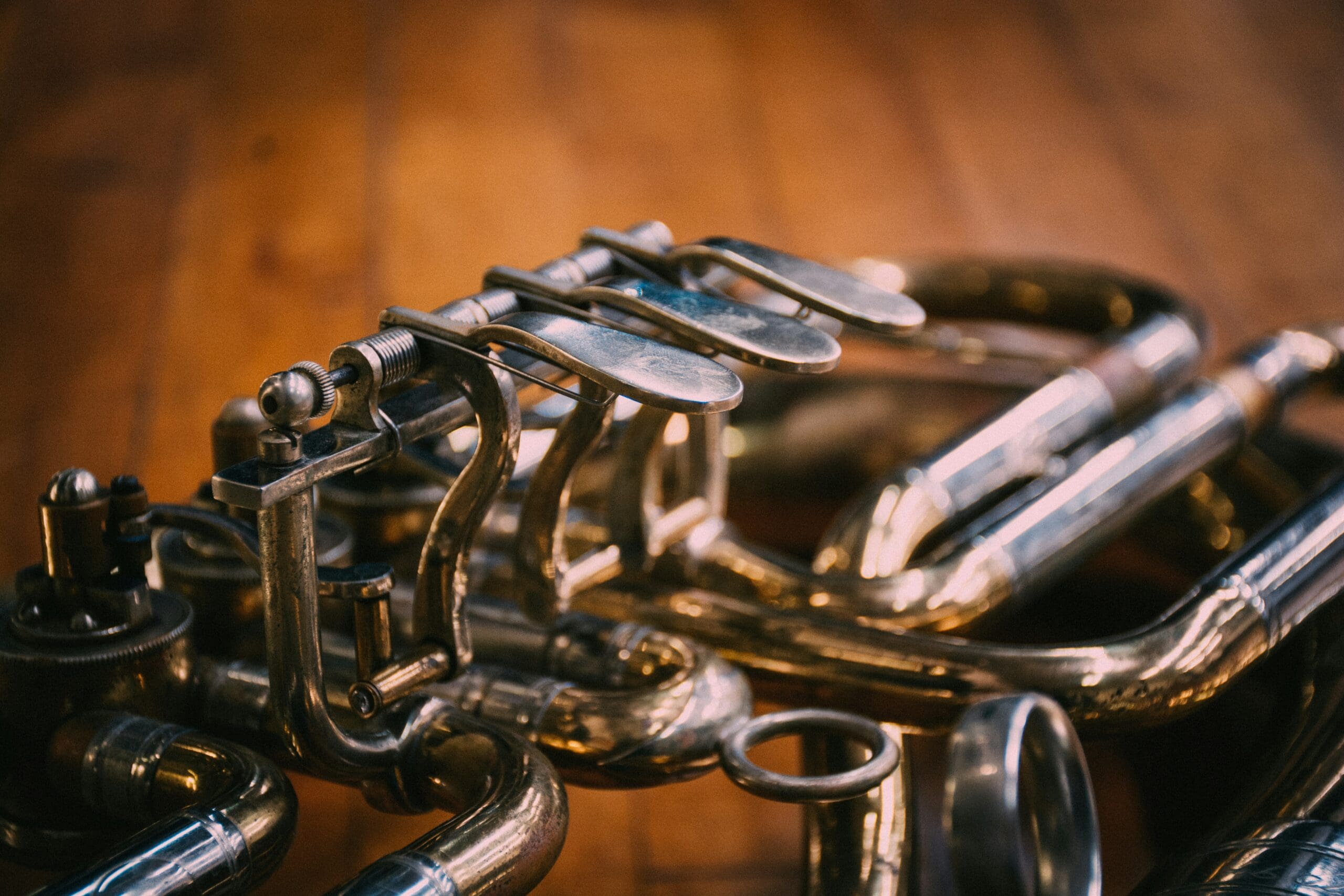 Close-up of polished brass instrument valves resting on a wooden floor