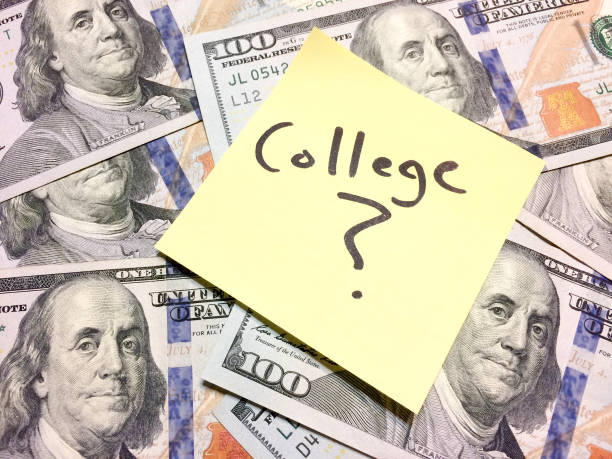 A yellow sticky note with the word “College?” written on it, placed on top of U.S. hundred-dollar bills.