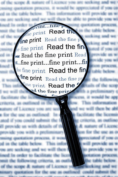 Magnifying glass enlarging the words “Read the fine print” on a document