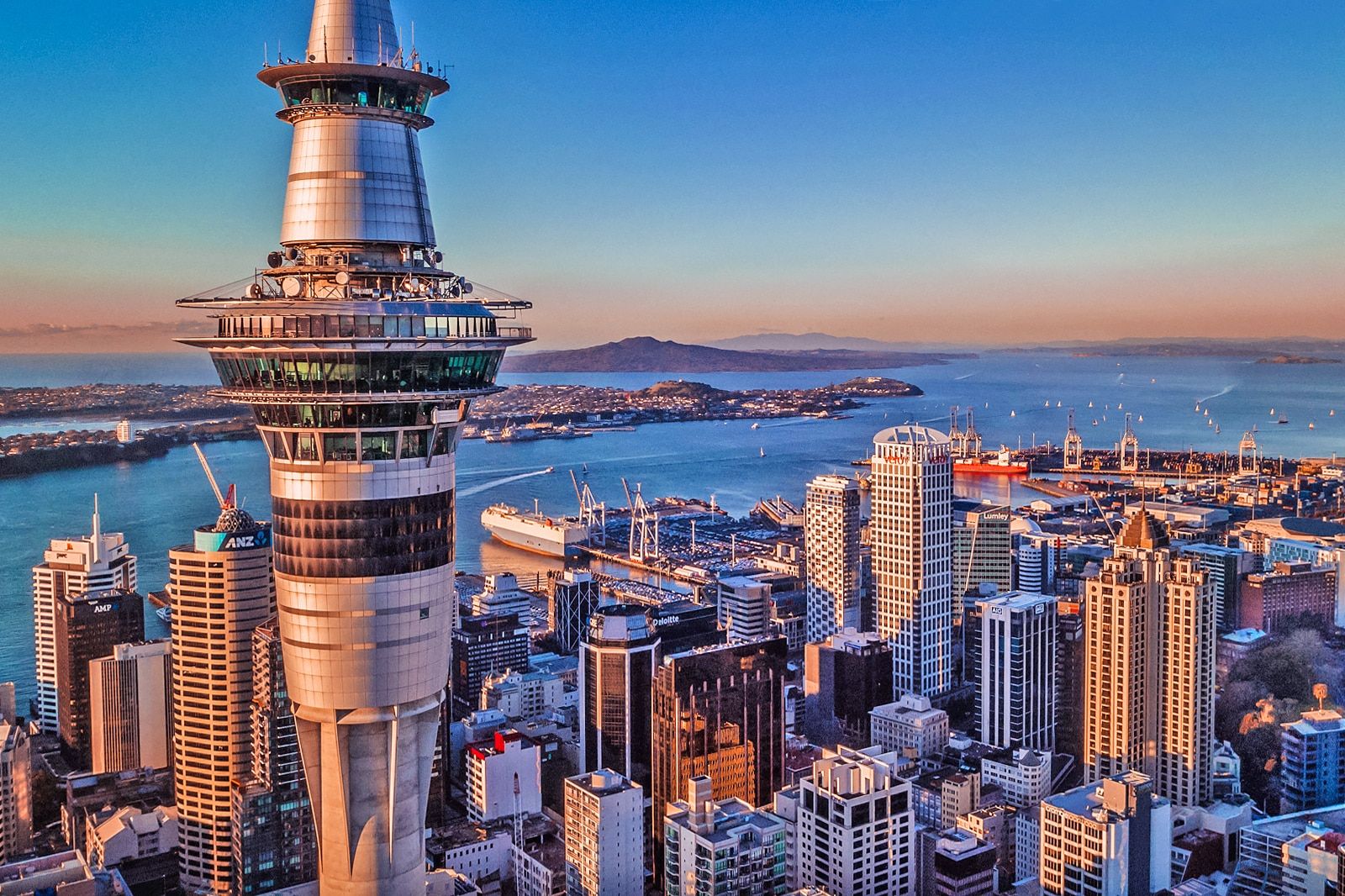 Auckland skyline at sunset with the Sky Tower overlooking the harbor and downtown buildings