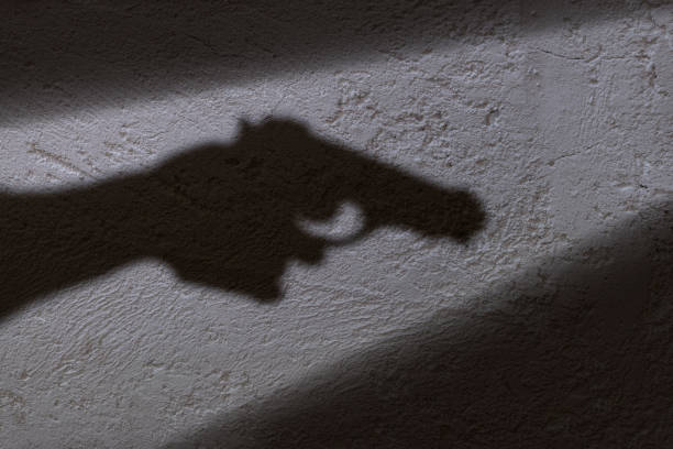 Shadow of a hand shaped like a gun projected onto a textured wall.