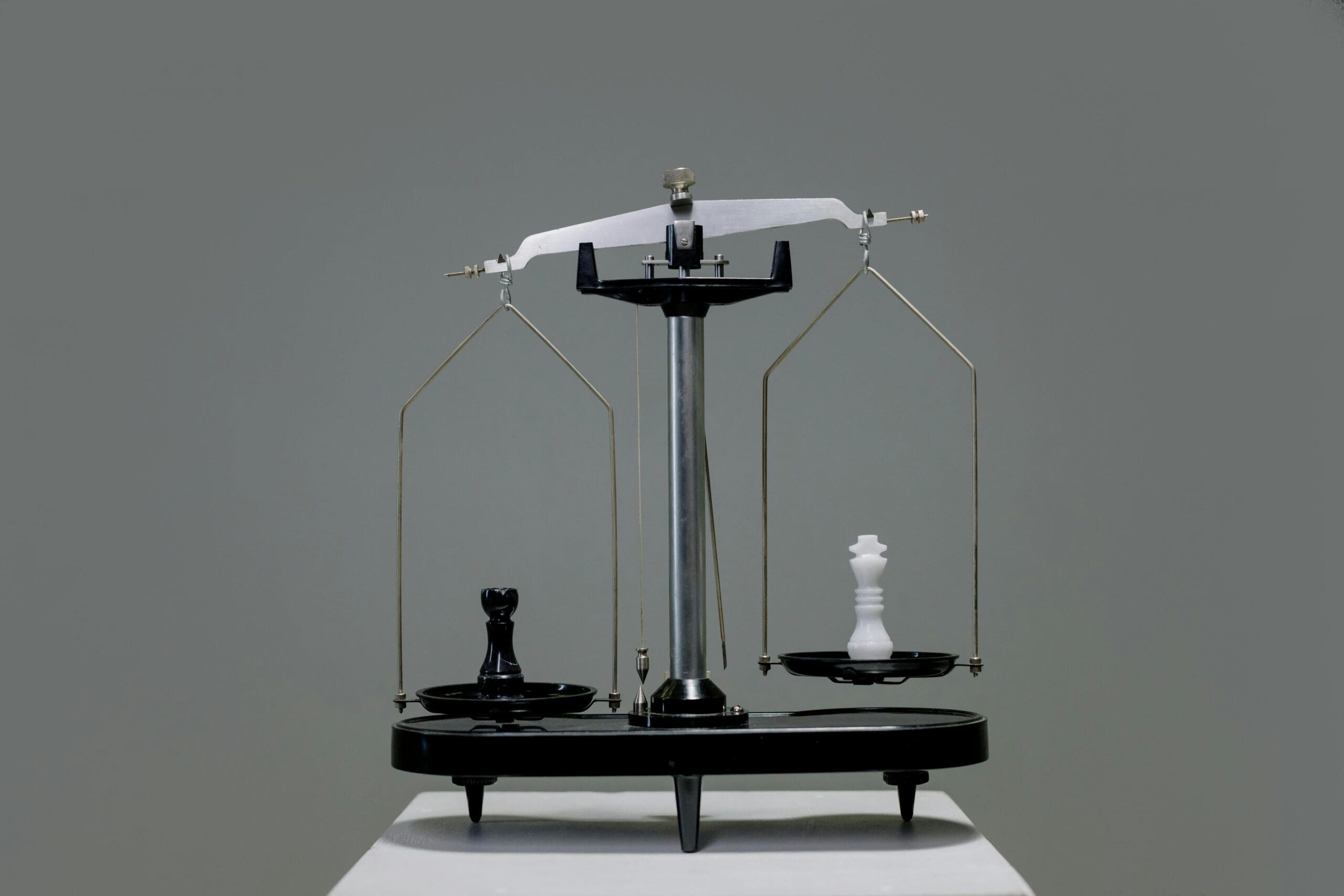 A vintage balance scale with a black rook and a white king chess piece placed on opposite trays, symbolizing imbalance or contrasting values.