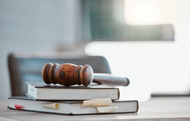 Wooden gavel resting on top of stacked law books with bookmarks.