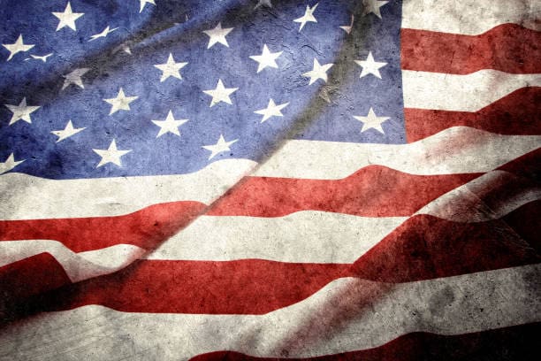A weathered and wrinkled American flag, showing visible texture and folds in the red, white, and blue fabric.