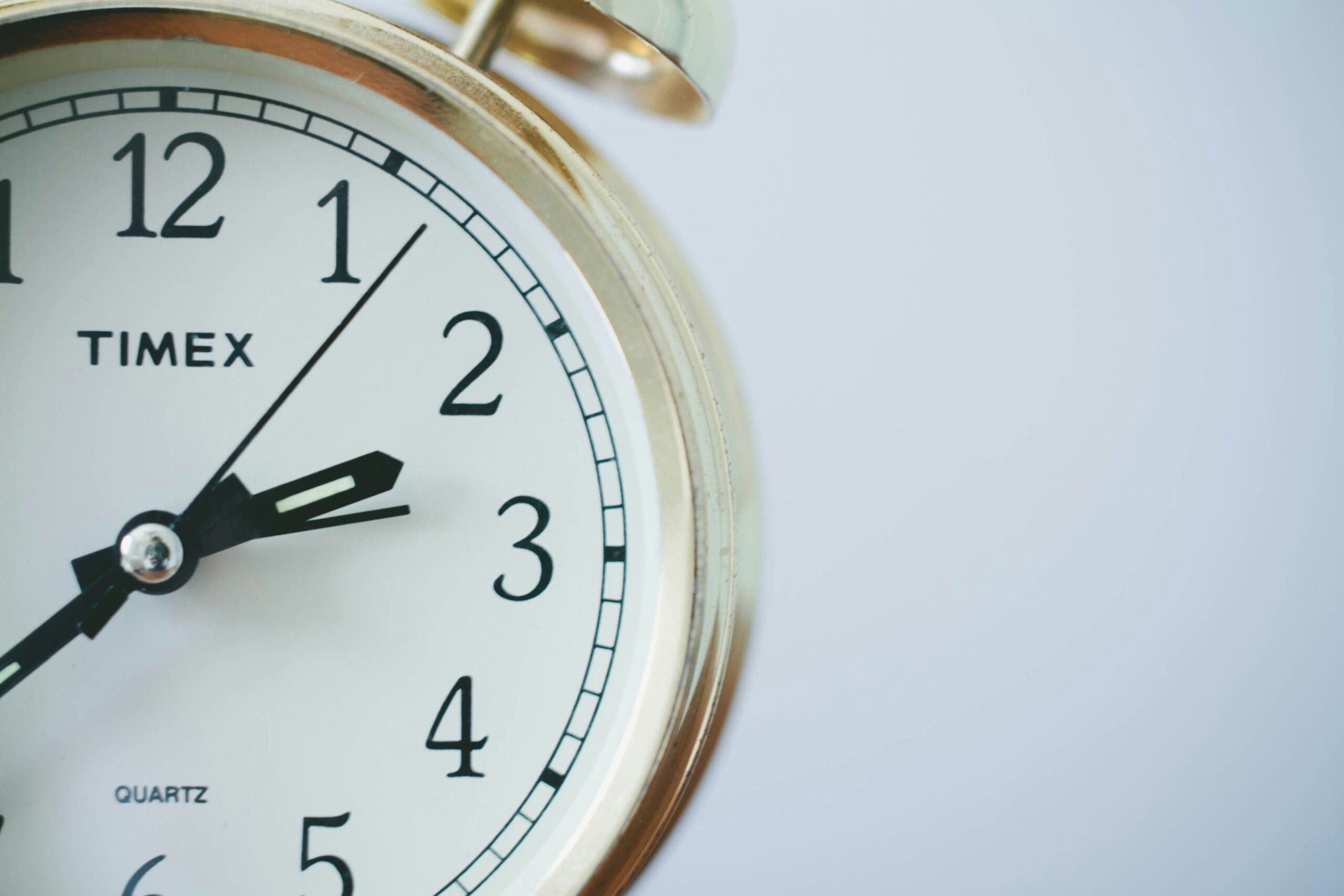 Close-up of a white Timex clock showing the time at 1:52 against a light background.